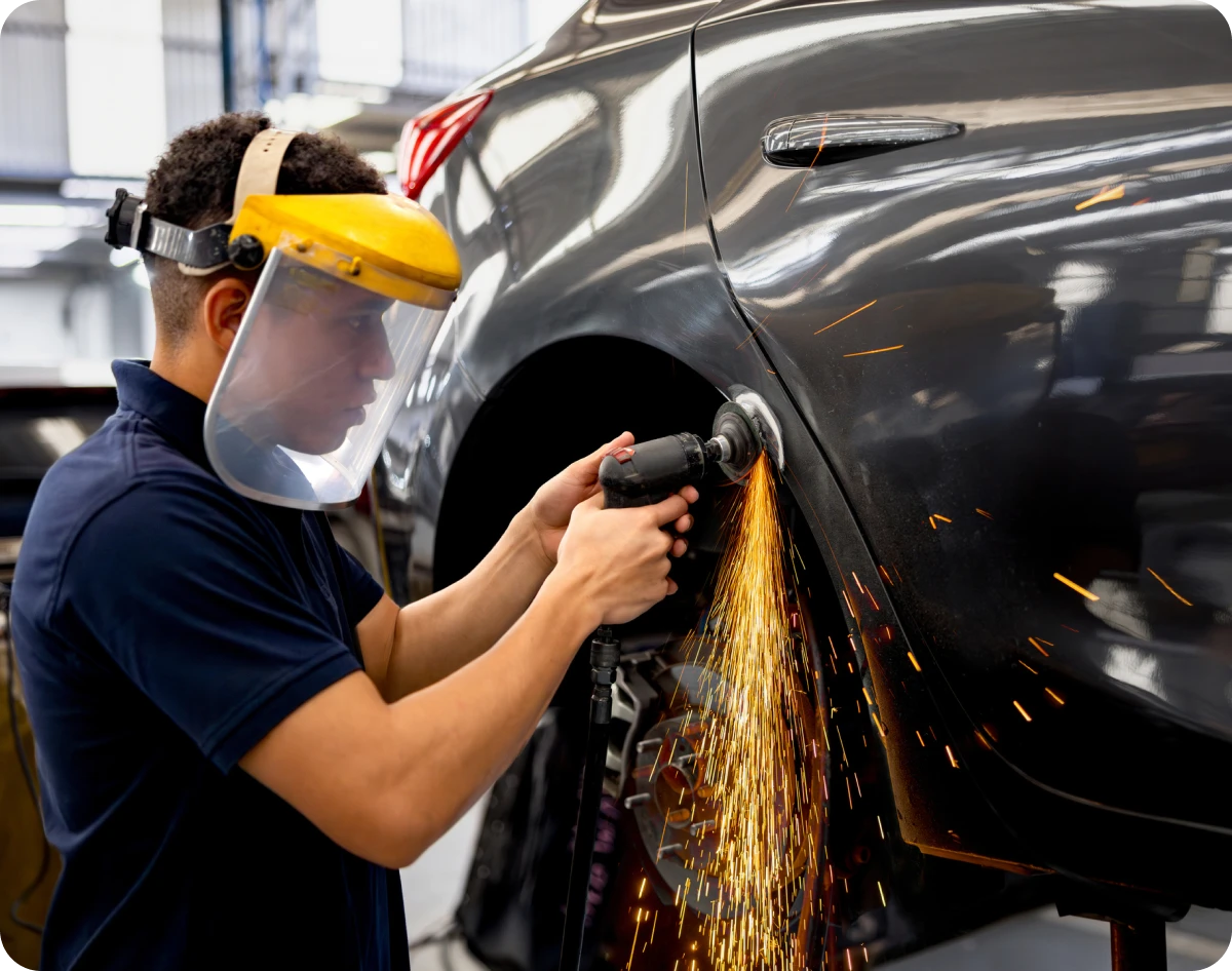Worker polishing car body in garage
